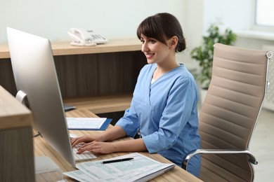 Photo of Smiling medical assistant working with computer in office
