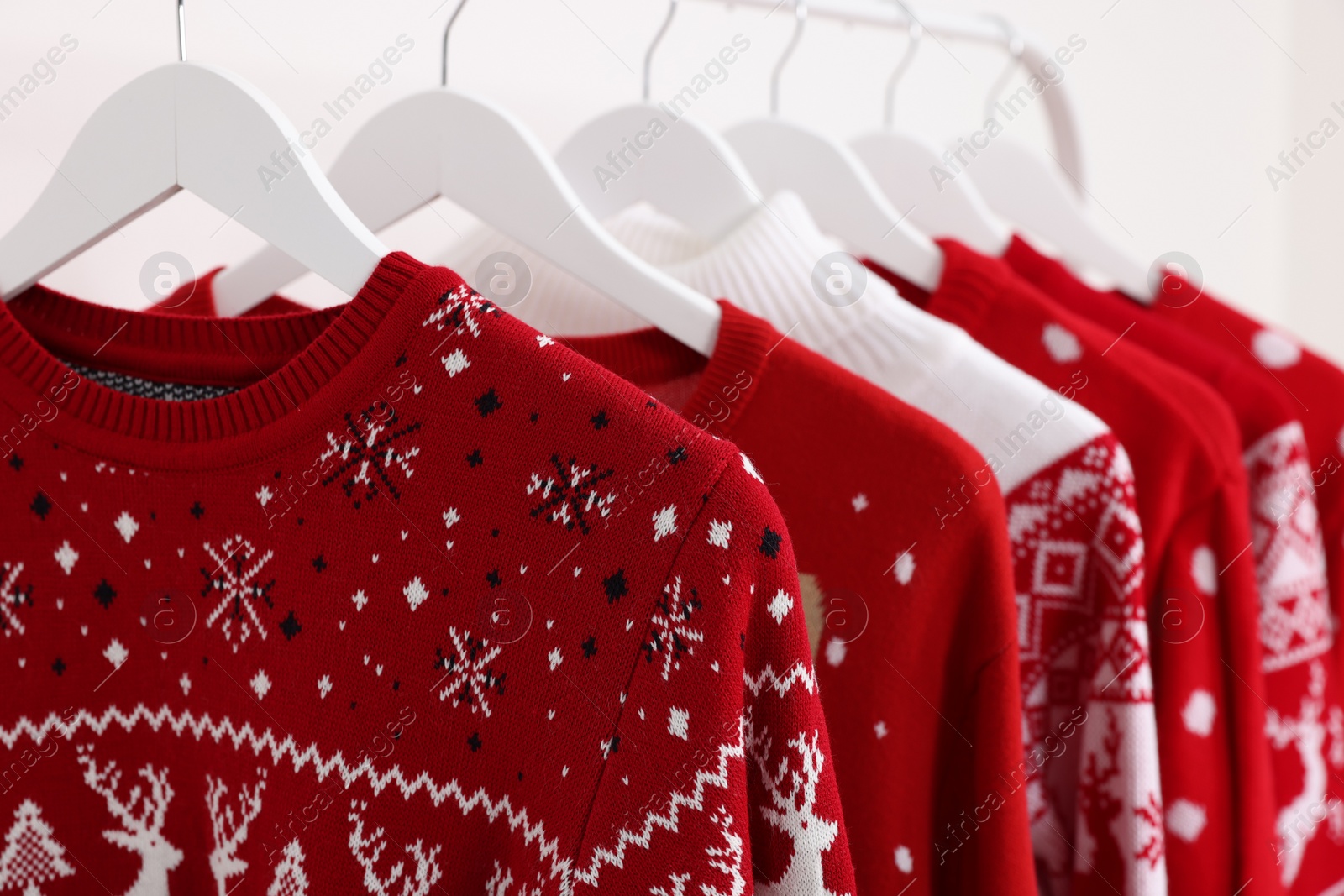 Photo of Rack with different Christmas sweaters on white background, closeup