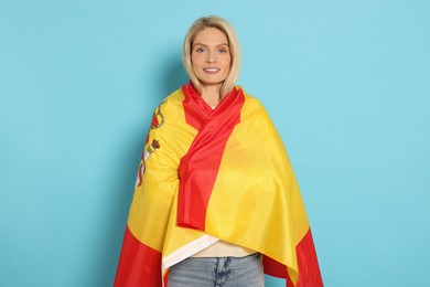 Woman with flag of Spain on light blue background