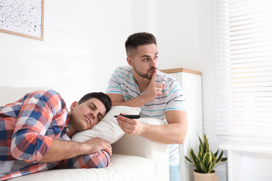 Young man with marker near sleeping friend indoors. April fool's day