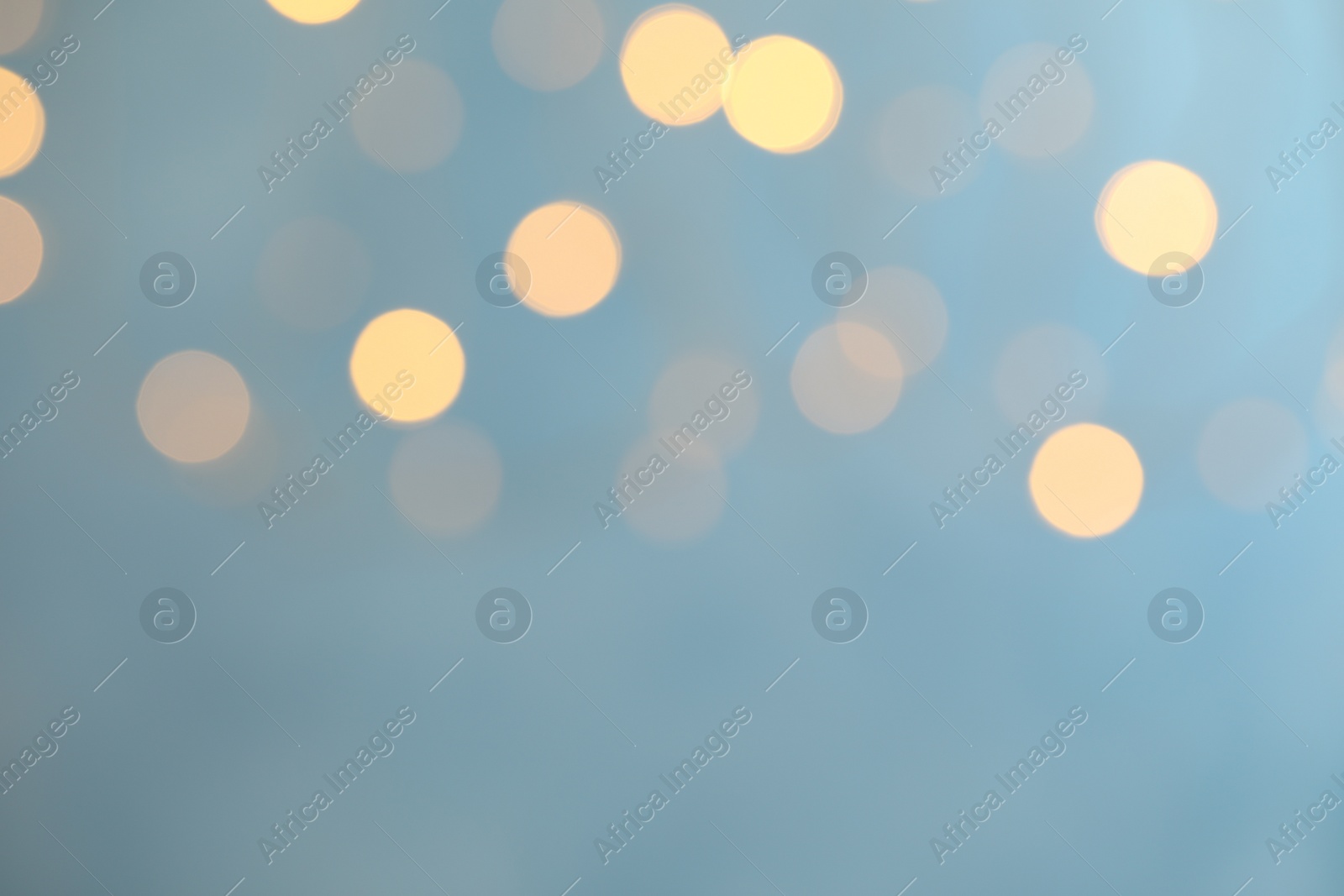 Photo of Blurred view of festive lights on light blue background. Bokeh effect