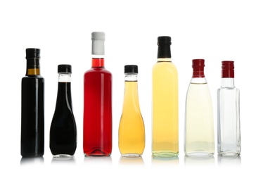 Photo of Bottles with different kinds of vinegar on white background