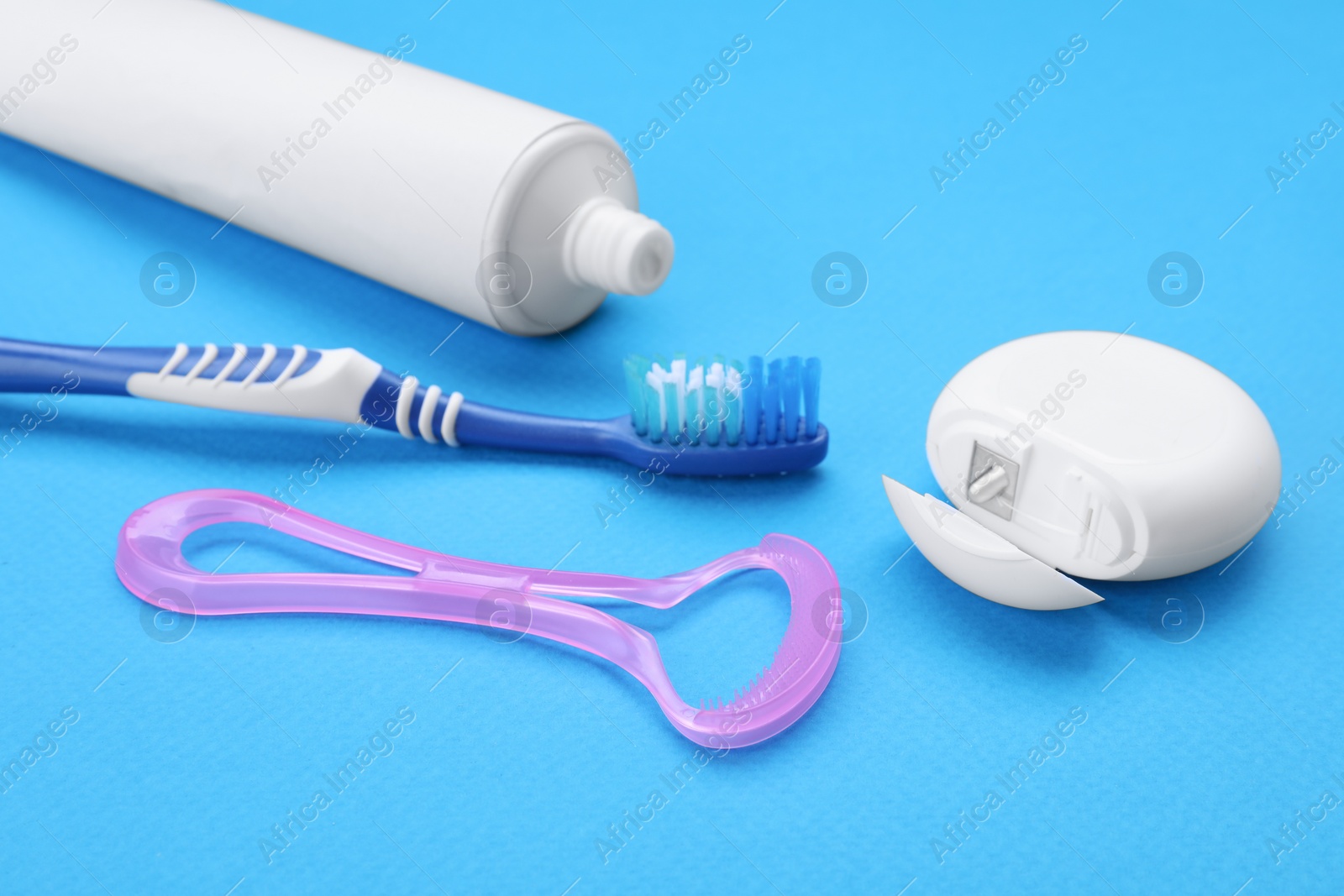 Photo of Tongue cleaner and other oral care products on blue background, closeup