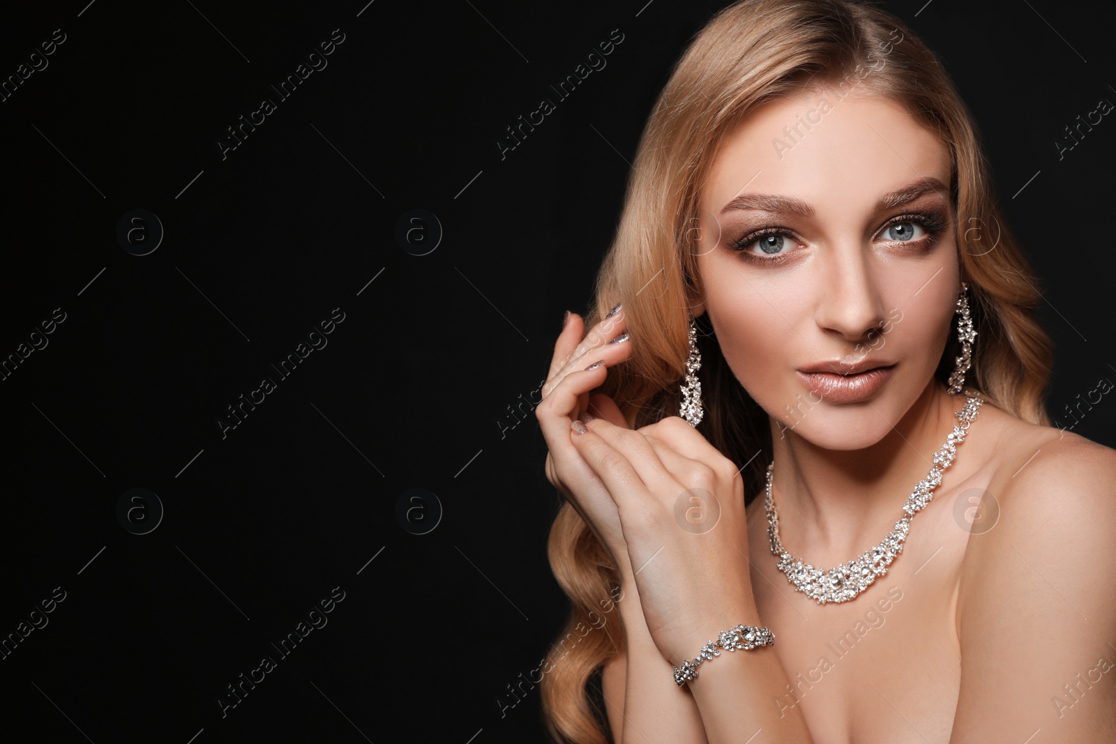 Photo of Beautiful young woman with elegant jewelry on dark background. Space for text