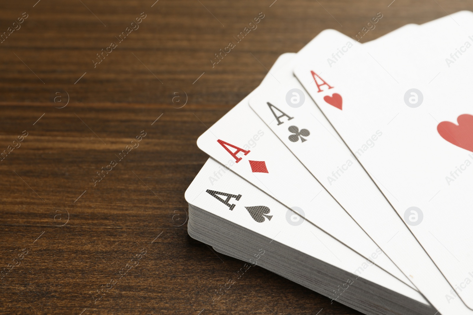 Photo of Four aces playing cards on wooden table, closeup. Space for text