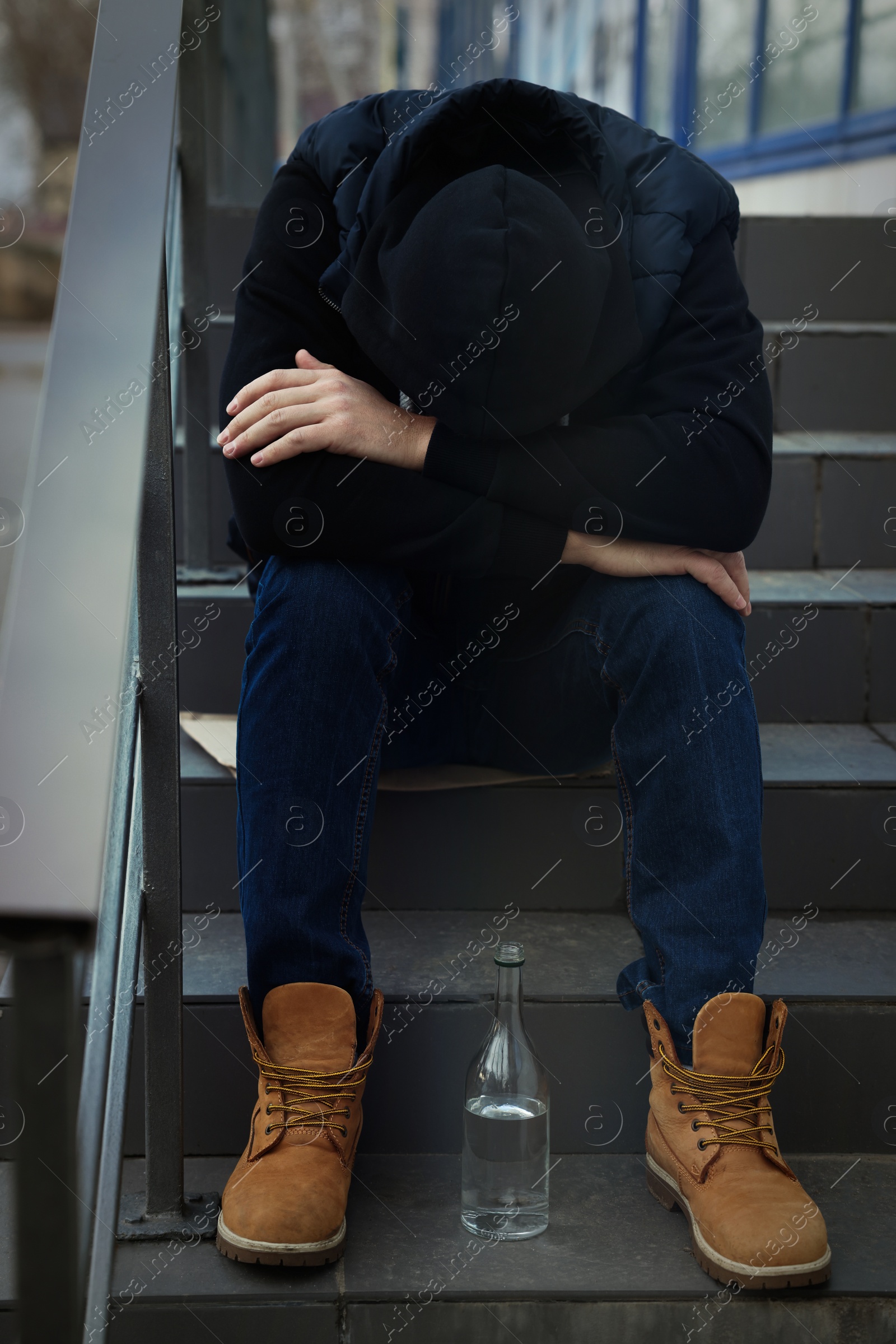 Photo of Addicted drunk man with alcoholic drink on stairs outdoors