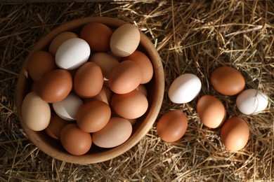 Photo of Fresh chicken eggs on dried straw, top view