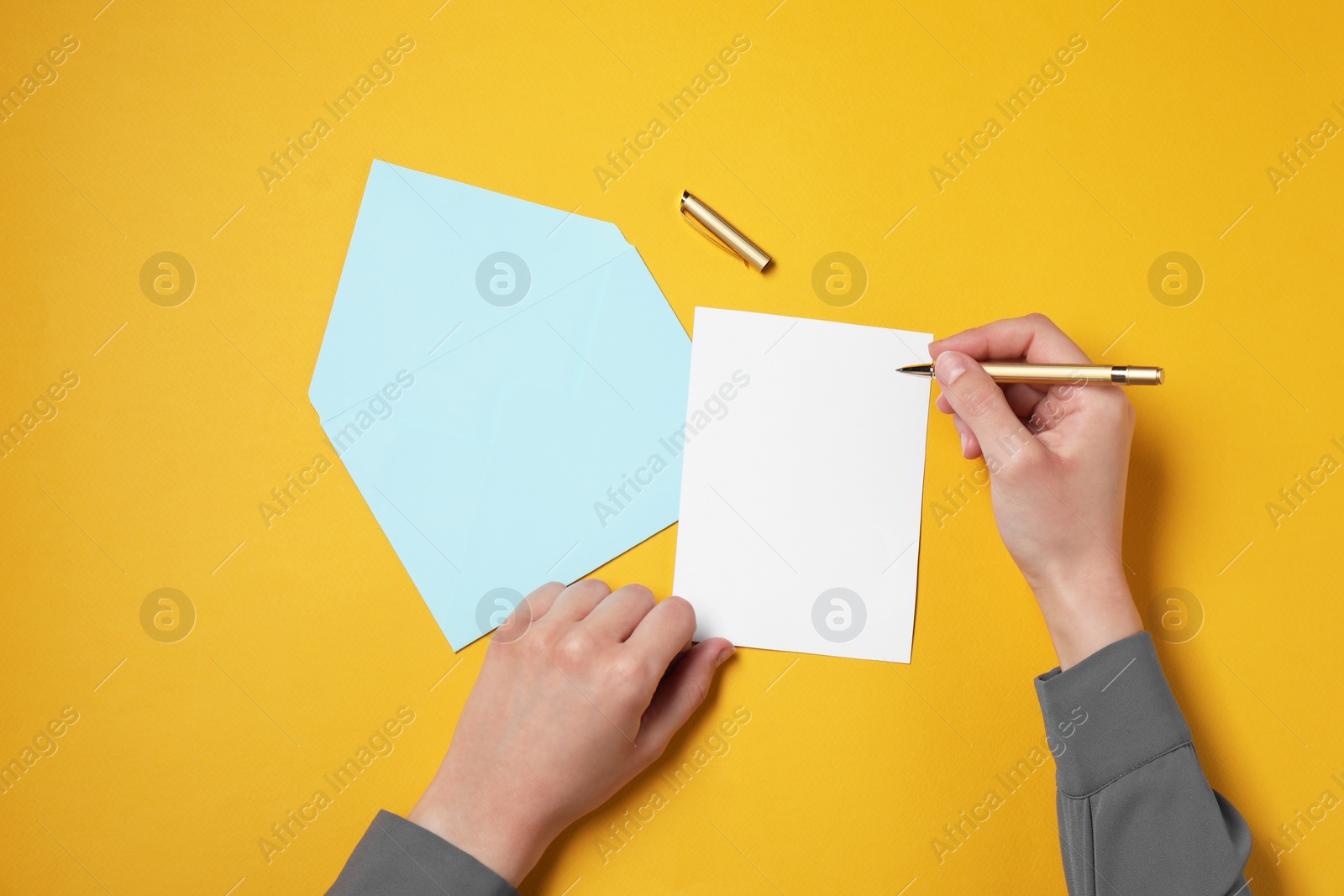 Photo of Woman writing letter at orange table, top view. Space for text