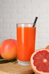 Photo of Tasty grapefruit juice in glass and fresh fruits on table, closeup