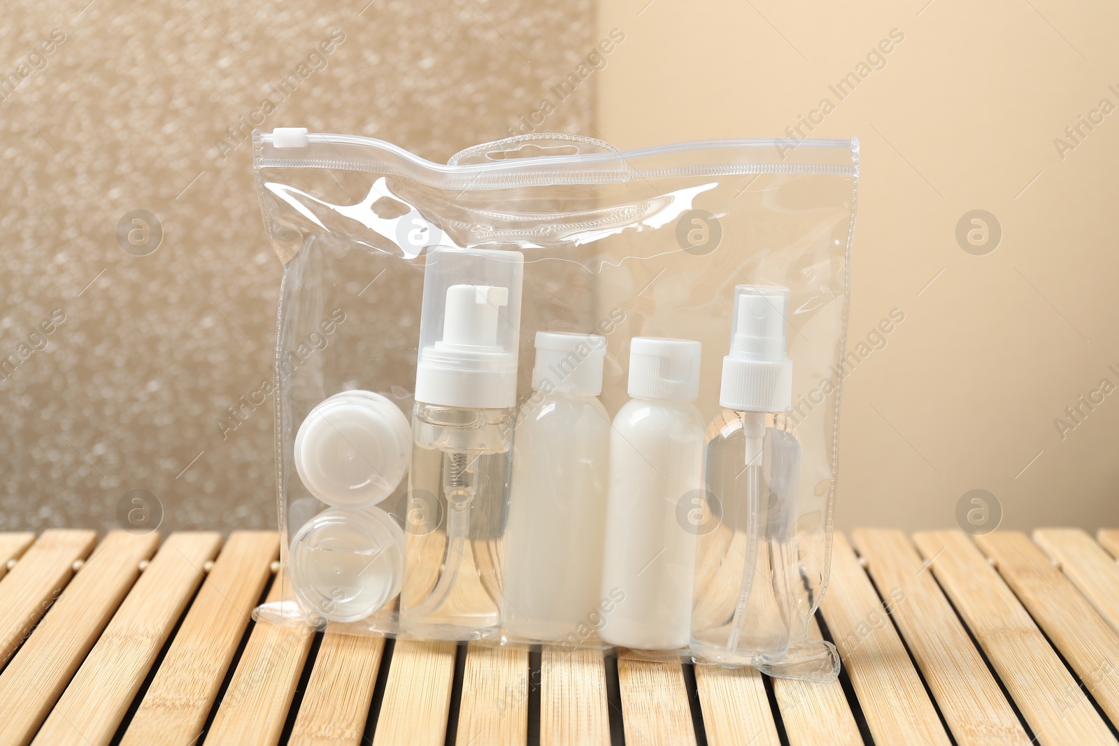 Photo of Cosmetic travel kit in plastic bag on wooden table. Bath accessories