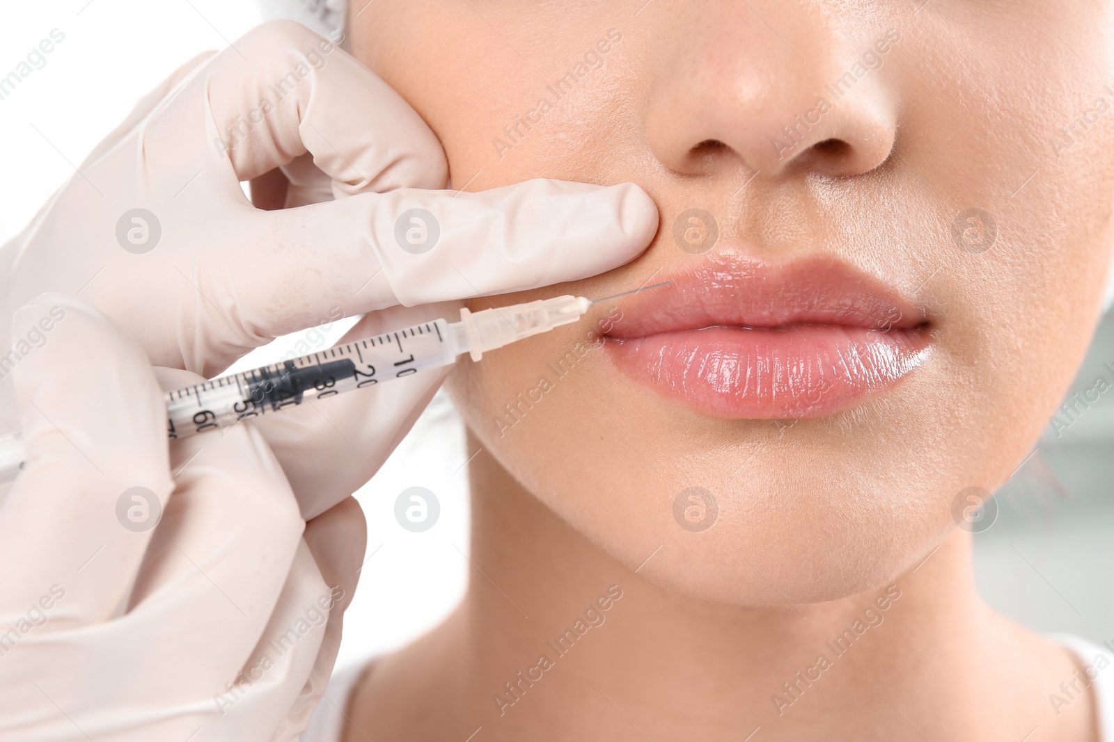 Photo of Young woman getting lip injection in beautician salon, closeup