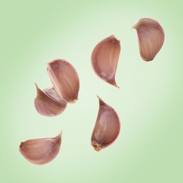 Image of Fresh garlic cloves falling on pale green background