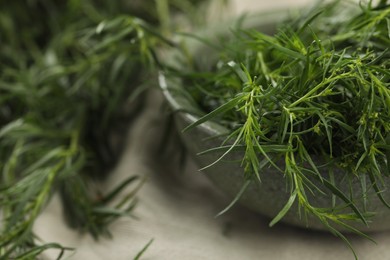 Photo of Fresh tarragon leaves in bowl on table, closeup