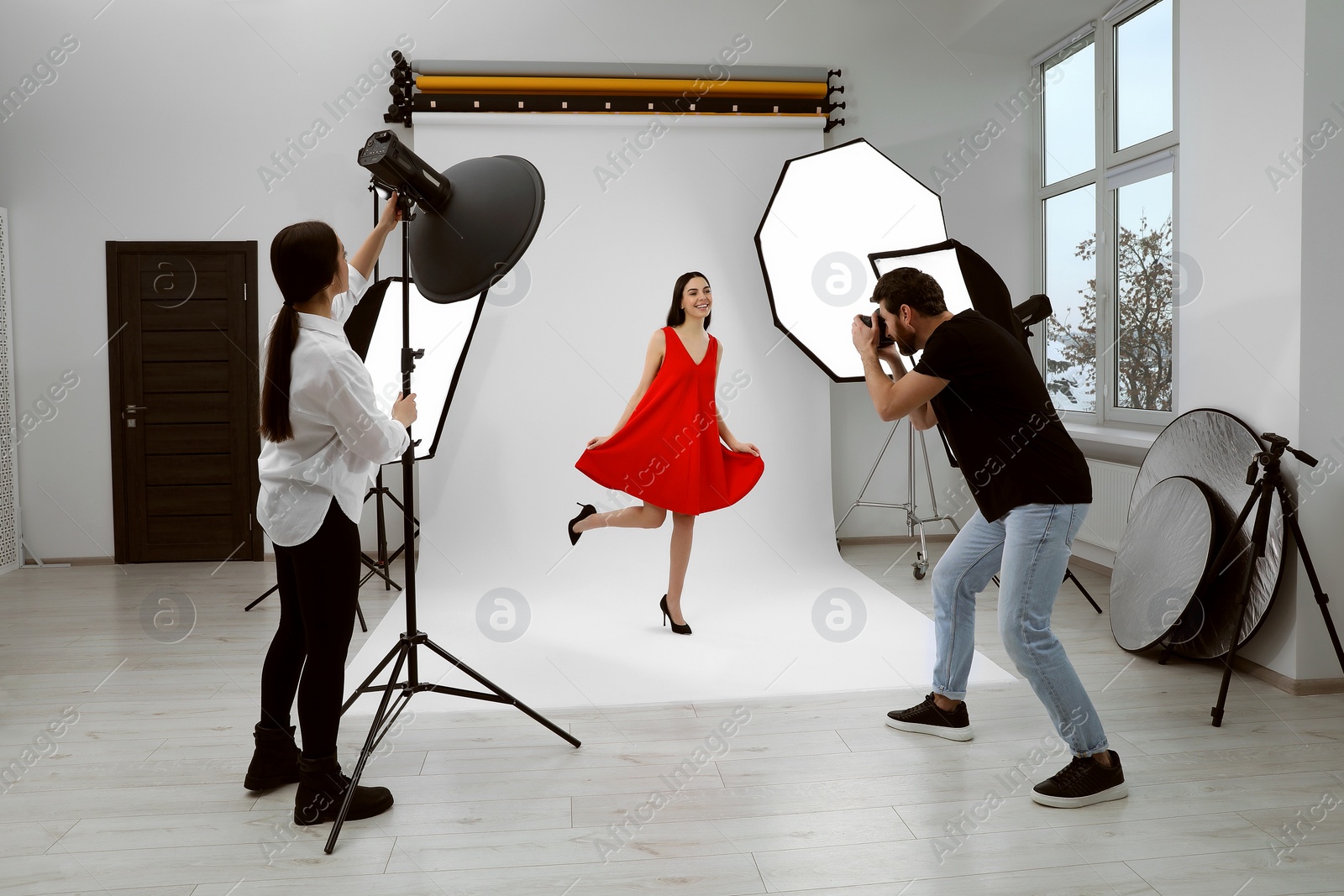 Photo of Professional photographer and assistant working with beautiful model in modern photo studio