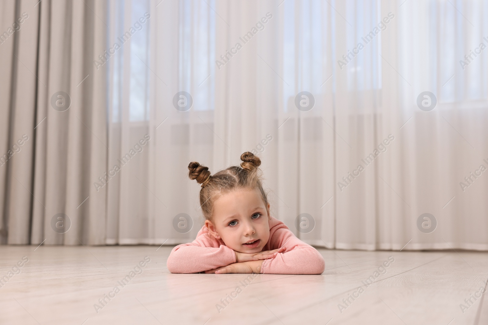 Photo of Cute little girl lying on warm floor at home. Heating system