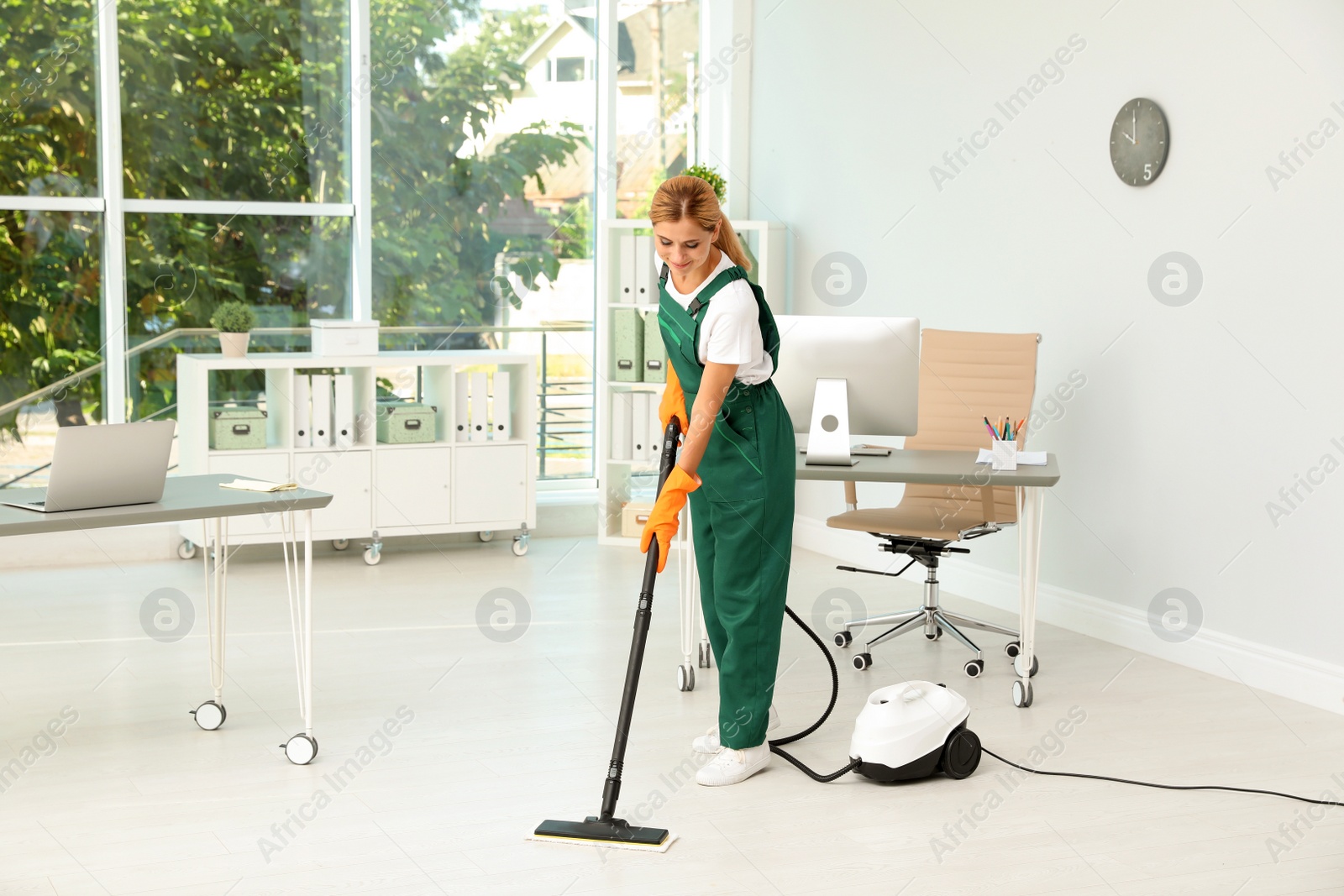 Photo of Female janitor in uniform cleaning office floor