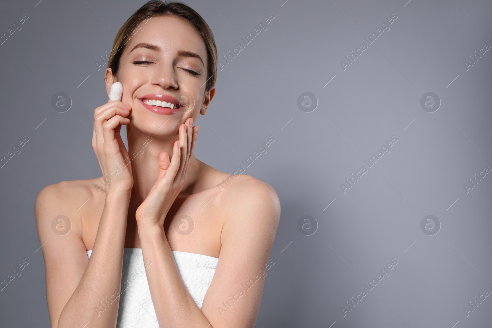 Photo of Woman using silkworm cocoon in skin care routine on grey background. Space for text