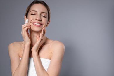 Woman using silkworm cocoon in skin care routine on grey background. Space for text