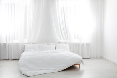 Photo of Comfortable bed in light room. Interior design