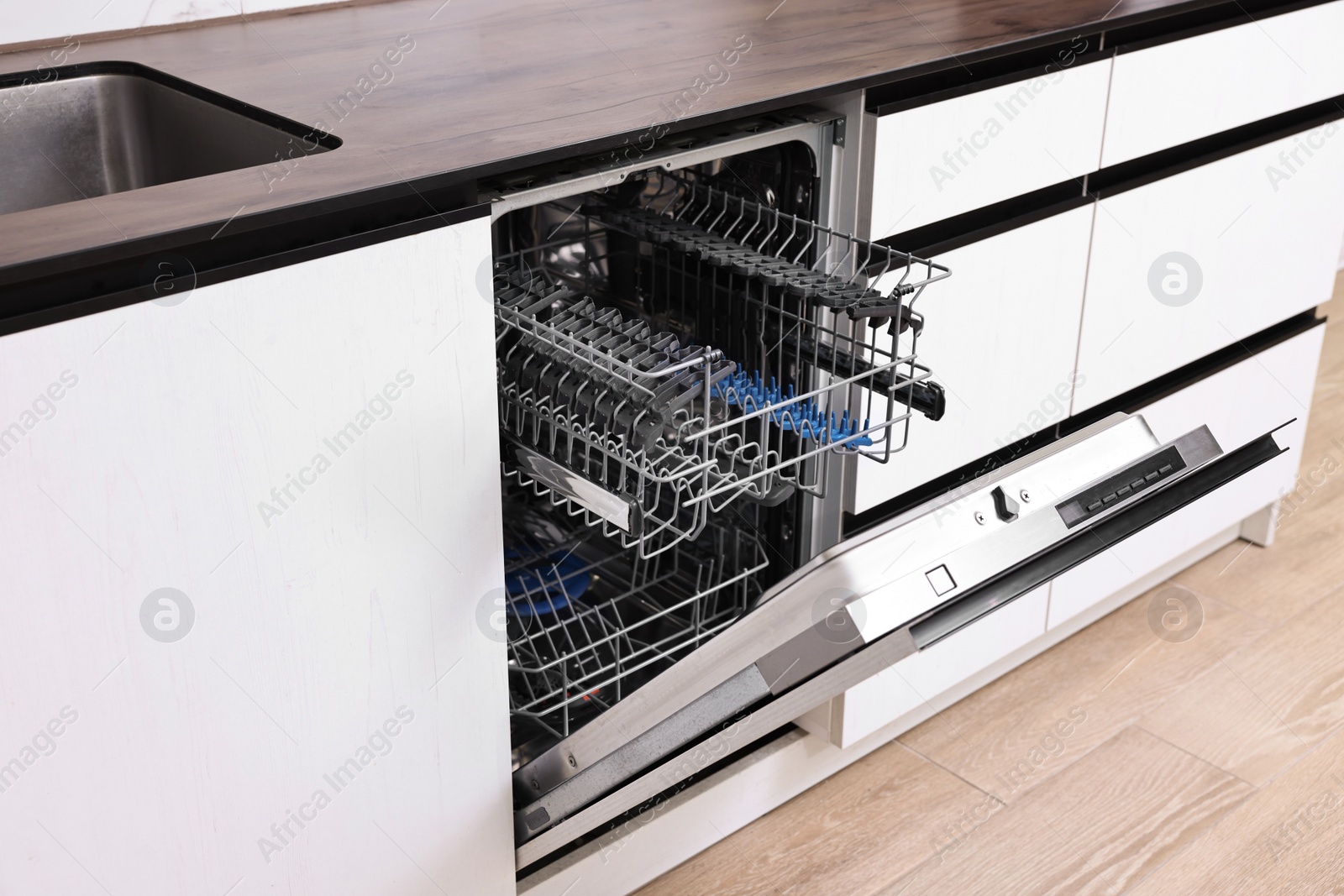 Photo of Built-in dishwasher with open door indoors. Home appliance