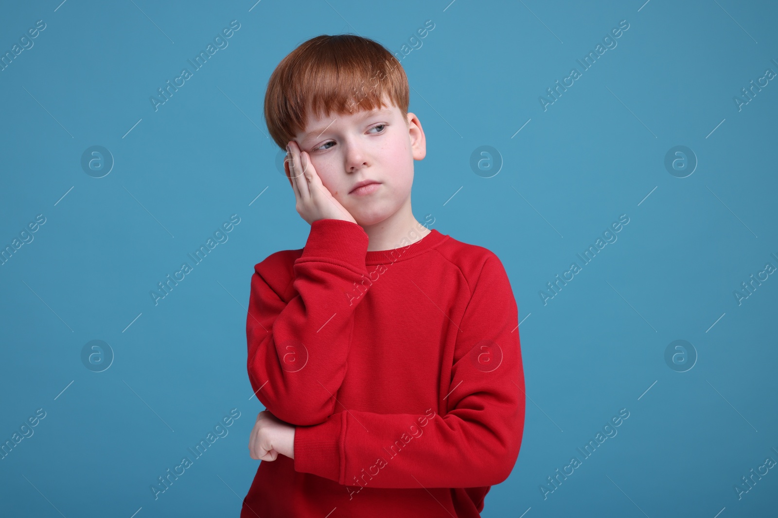 Photo of Portrait of sad little boy on light blue background