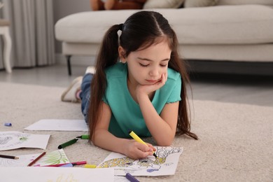 Photo of Cute child coloring drawing on floor at home