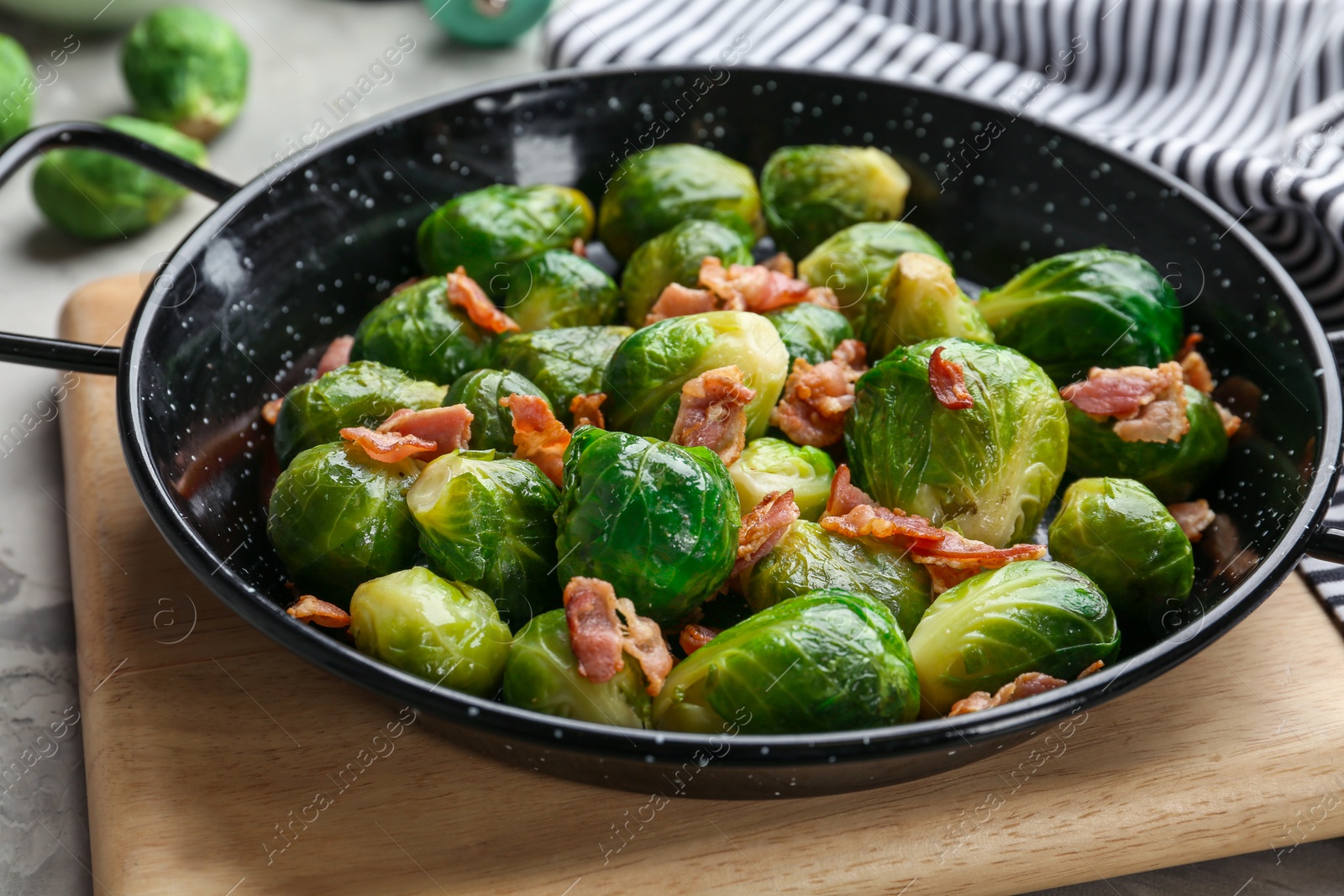 Photo of Tasty roasted Brussels sprouts with bacon on light grey table, closeup