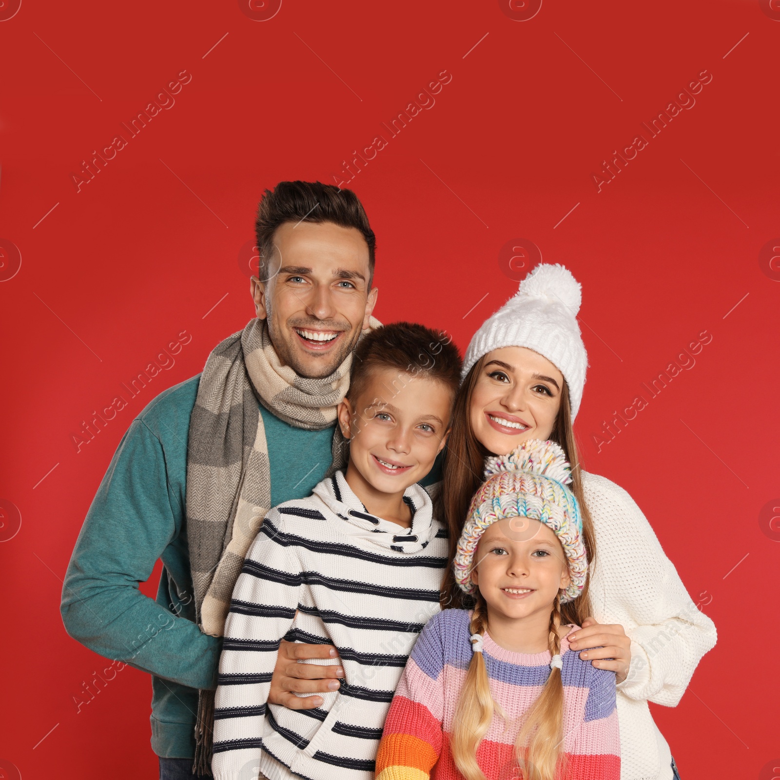 Photo of Happy family in warm clothes on red background. Winter season