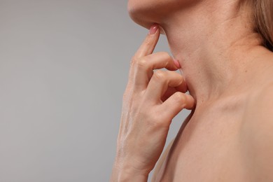 Photo of Woman touching her neck on grey background, closeup. Space for text