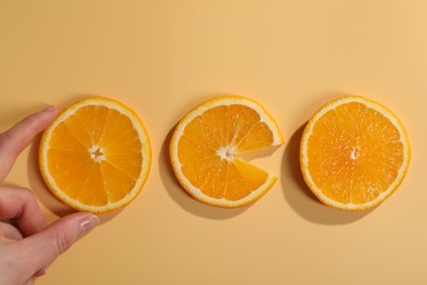 Photo of Woman with slices of juicy orange on beige background, top view