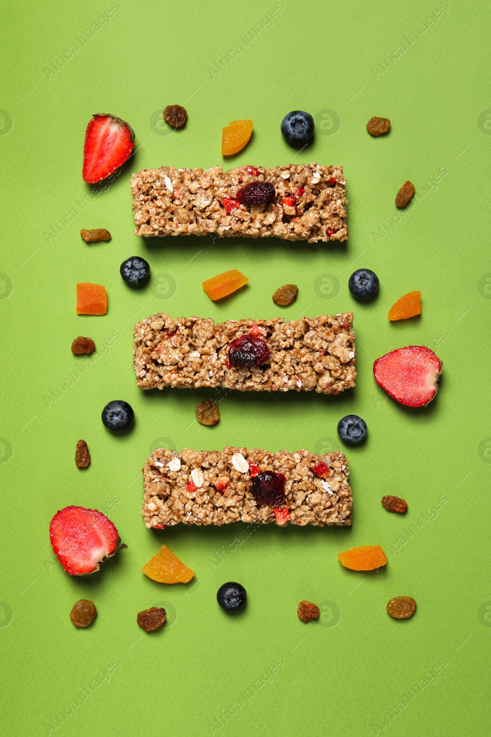 Photo of Tasty granola bars and ingredients on green background, flat lay