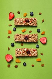 Tasty granola bars and ingredients on green background, flat lay