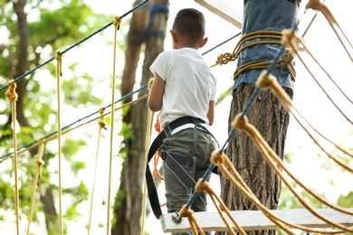 Little African-American boy climbing in adventure park, back view. Summer camp