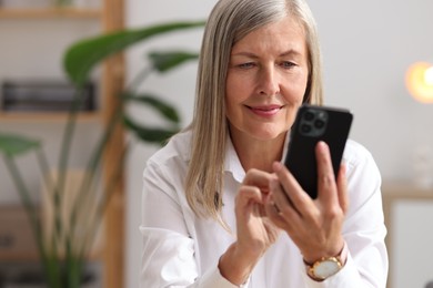 Photo of Senior woman using mobile phone at home