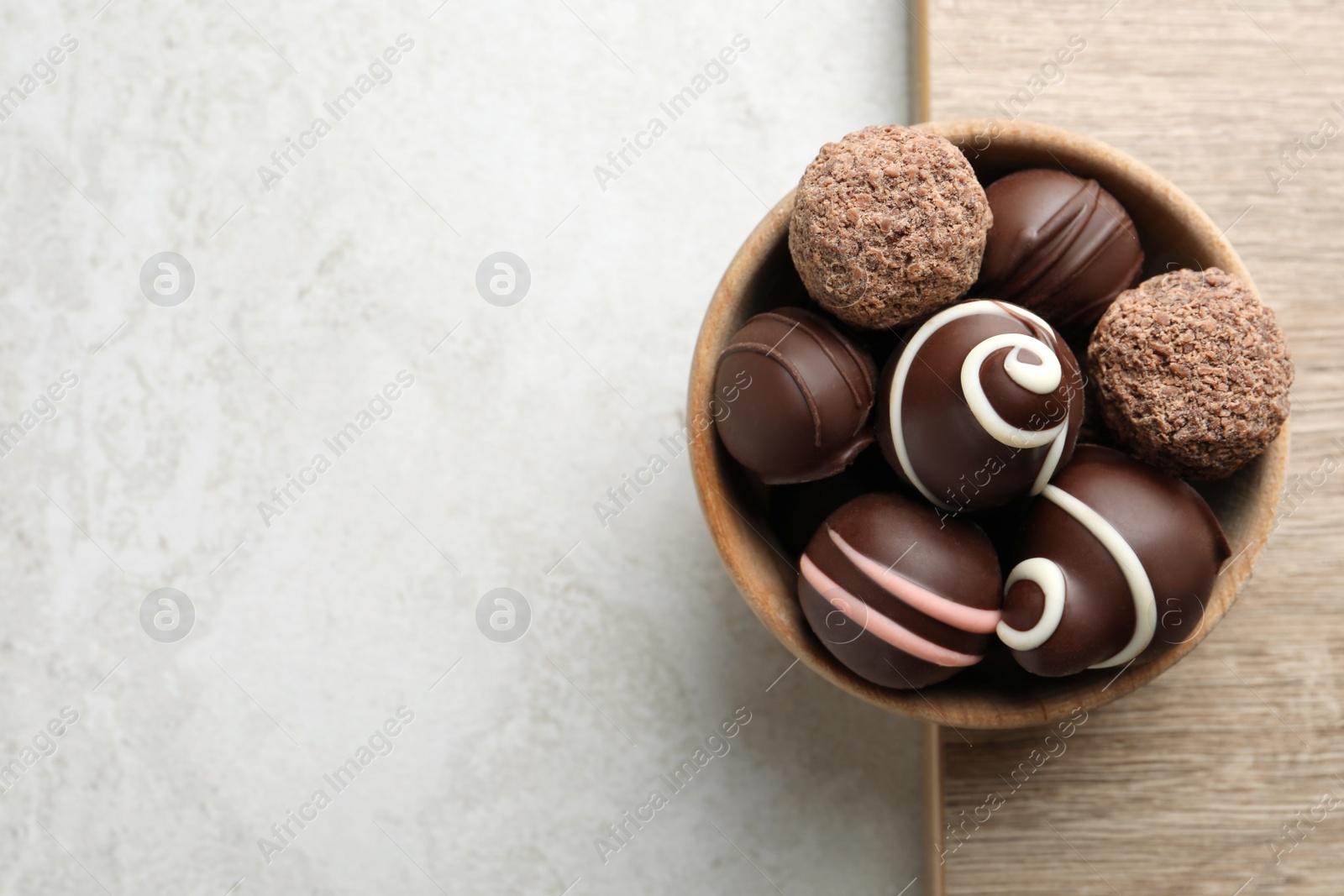 Photo of Many different delicious chocolate truffles on light table, top view. Space for text