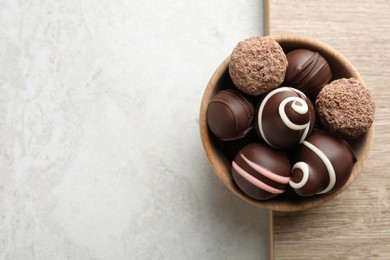 Many different delicious chocolate truffles on light table, top view. Space for text