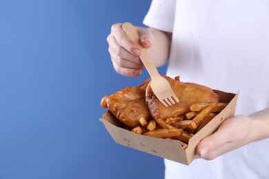 Photo of Woman eating fish and chips on blue background, closeup. Space for text