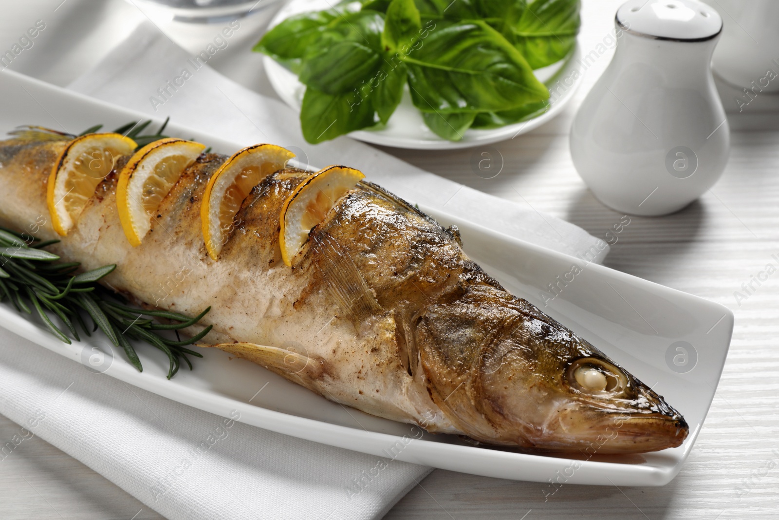 Photo of Tasty homemade roasted pike perch served on white wooden table, closeup. River fish