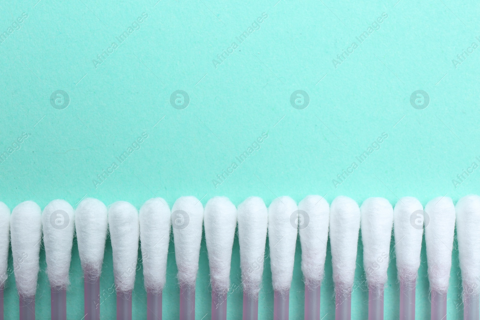 Photo of Many cotton buds on turquoise background, flat lay. Space for text