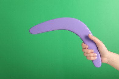 Photo of Woman holding boomerang on green background, closeup