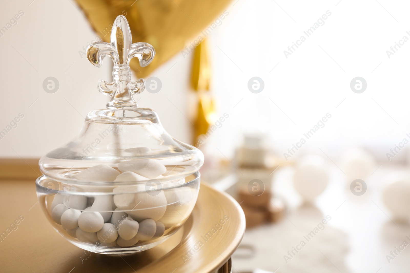 Photo of Glass jar with treats on golden table in light room