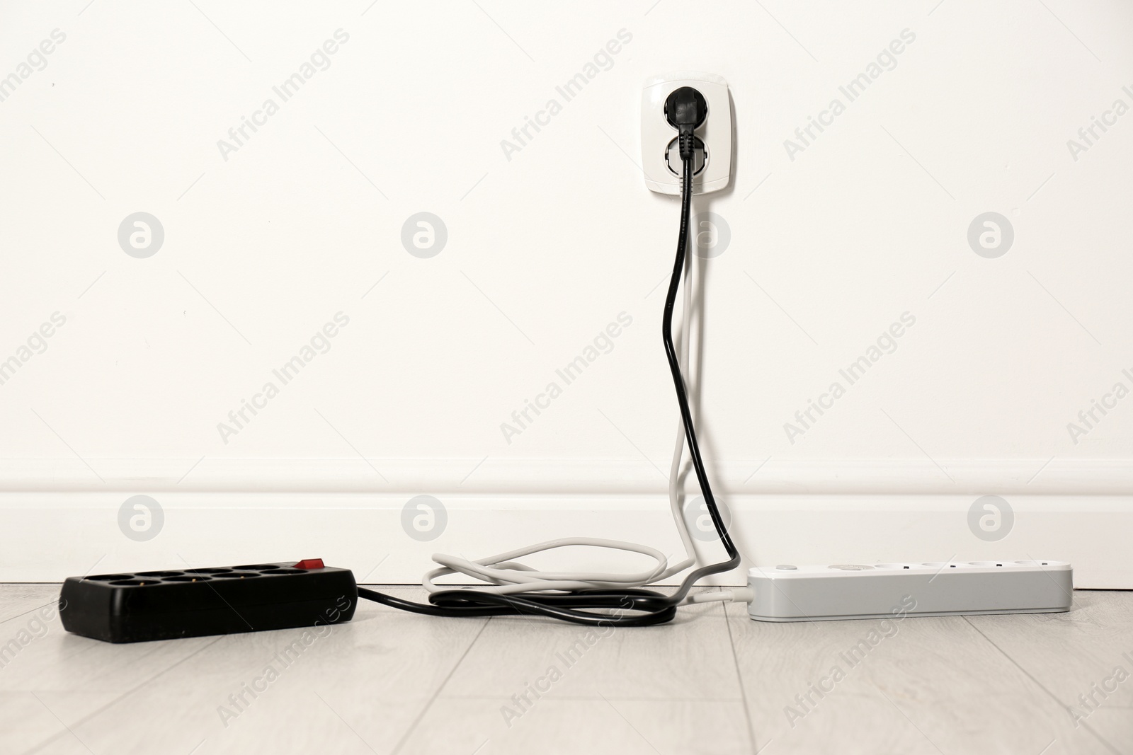 Photo of Extension cords with power plugs in socket indoors, space for text. Electrician's professional equipment