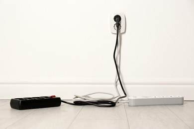 Extension cords with power plugs in socket indoors, space for text. Electrician's professional equipment