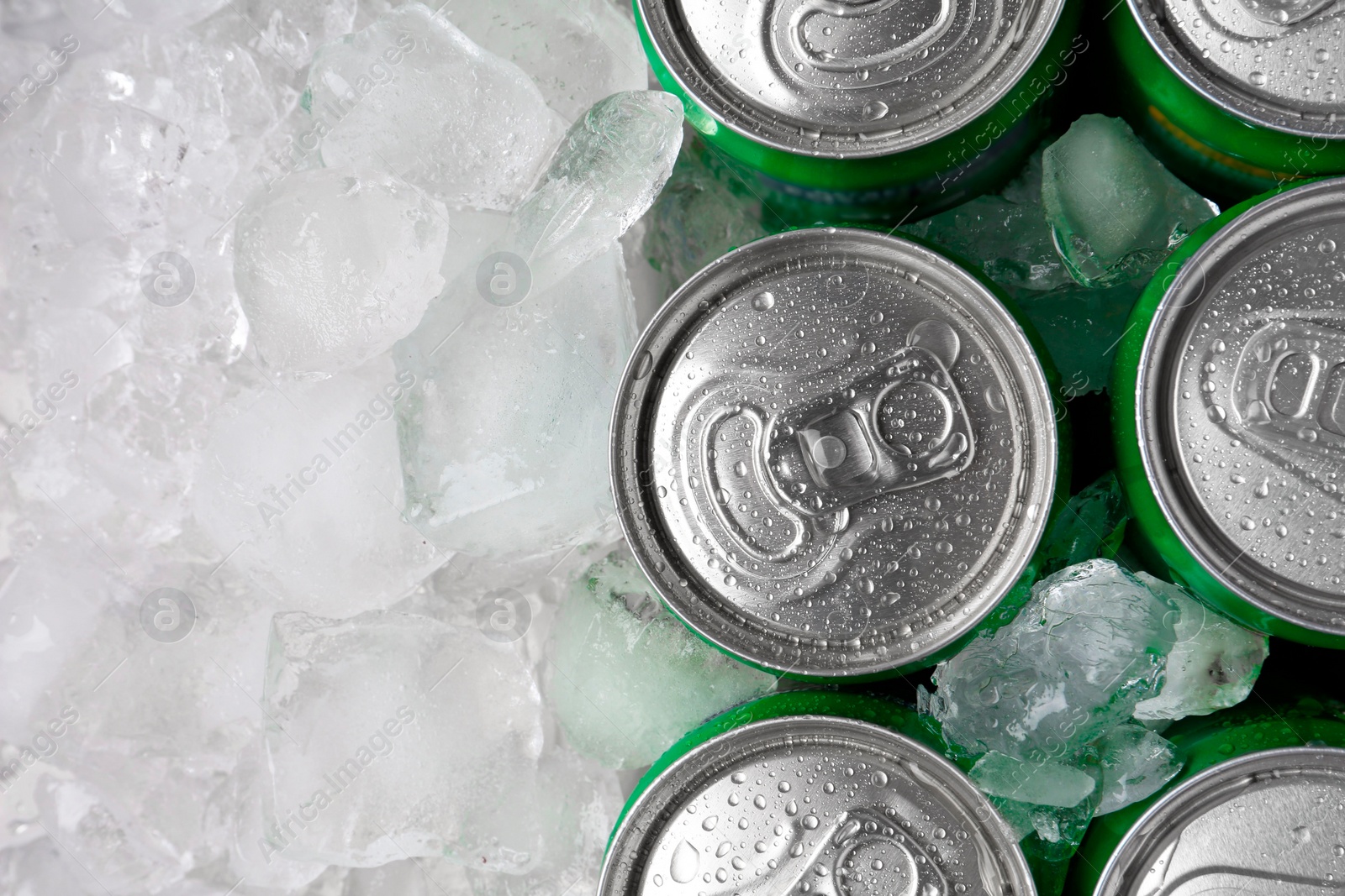 Photo of Energy drinks in wet cans and ice cubes, flat lay. Space for text