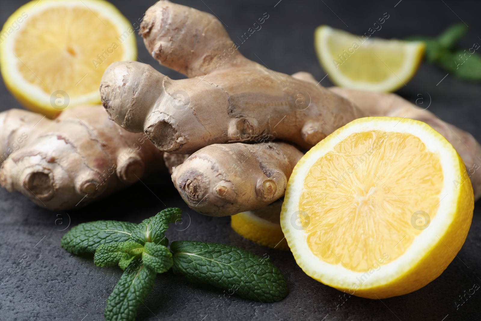 Photo of Fresh lemon, ginger and mint on grey table, closeup