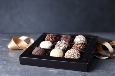 Photo of Delicious chocolate candies in box on light grey table