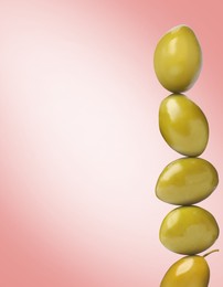 Image of Stack of whole olives on pink gradient background, space for text