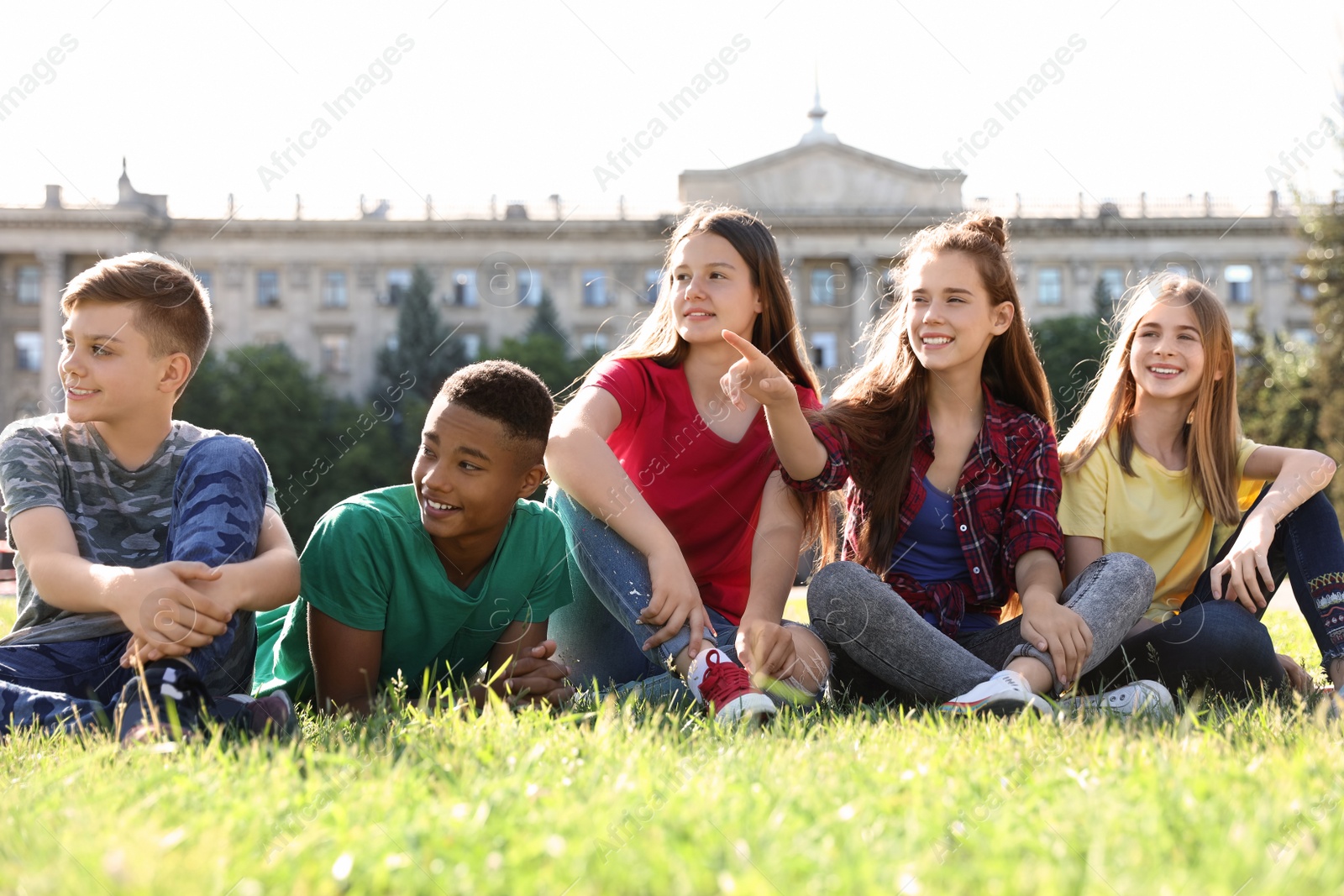 Photo of Group of children sitting on grass outdoors. Summer camp