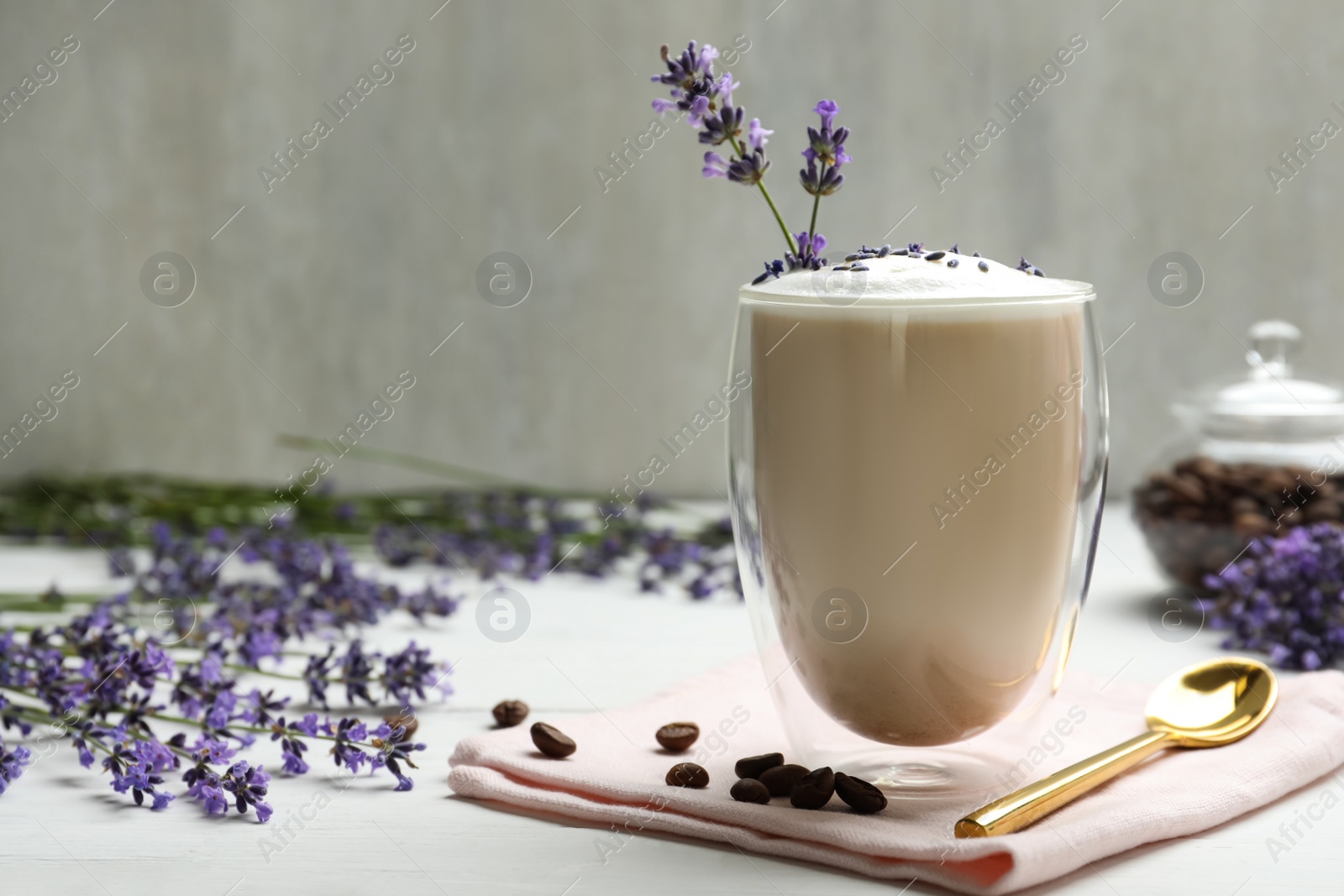 Photo of Delicious coffee with lavender and beans on white wooden table. Space for text