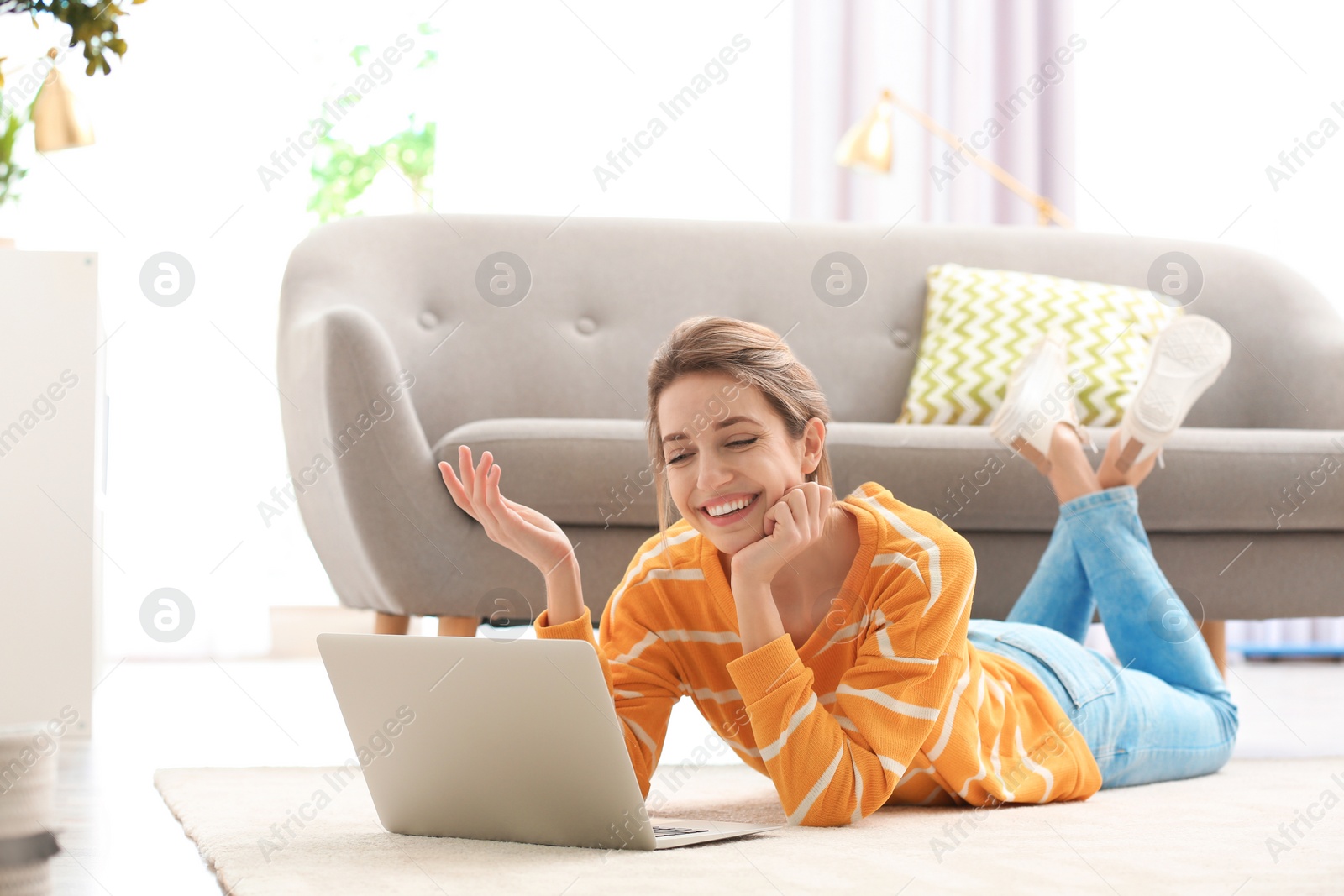 Photo of Woman using laptop for video chat in living room